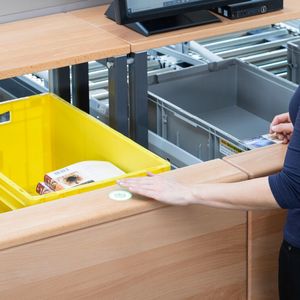 Die Waren werden bei der Kommissionierung mit der „Advanced-Pick-Station one-level“ von SSI Schäfer in Boxen auf ergonomischer Höhe abgelegt. Durch einfach zu bedienende Taster wird der Kommissioniervorgang bestätigt.