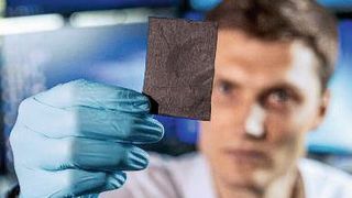 Victor Selmert zeigt das schwarze Vlies, dessen mikroskopische Fasern bestens zur Absorption von CO2 geeignet sind. (Bild: Forschungszentrum Jülich / A. Kretzschmar, V. Selmert)
