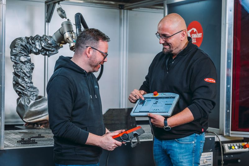 Umetec-Fertigungsleiter Tony Meyer (links) lässt sich vom Fronius-Anwendugstechniker Andreas Plumeier demonstrieren, wie man die Fronius-Smartcell teachen kann. Das klappe mit der Software Smartarc und dem Saep-Handgriff komfortabel und einfach. (Bild: Chr. Große pivopix / Fronius)