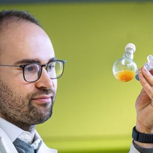 Dr. Philip Stanley kontrolliert einen Kolben, in dem sich das neue Material in einer wässrigen Lösung befindet(Bild:  Astrid Eckert – TUM)