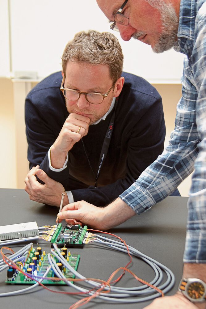 Bild 1: Thomas Klug im Gespräch mit Projektentwickler Martin Räuschl, Lacon Embedded, bei der Entwicklung des EAutoLaders. „Mit dem EAutolader werden teure und langwierige Aufrüstungen – also das Legen neuer Leitungen und teurer Versorgungspunkte – vermieden. Stattdessen wird das Nutzerverhalten verstanden und mittels einer intelligenten Steuerung in eine praktikable Lösung umgesetzt.“ Echtes „German Klimaengineering“.