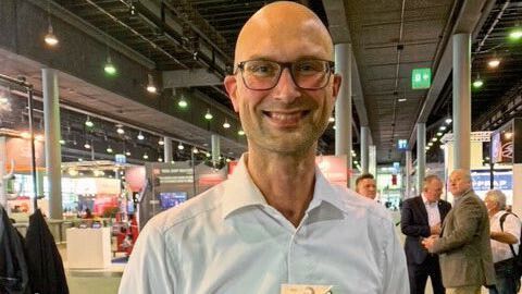 Stefan Meyer, Referent aus der Abteilung Öffentlichkeitsarbeit des ZDK, zeigt den Flyer des ZDK zu seiner neuen Kampagne „E10“. (Pfaff/»kfz-betrieb«)