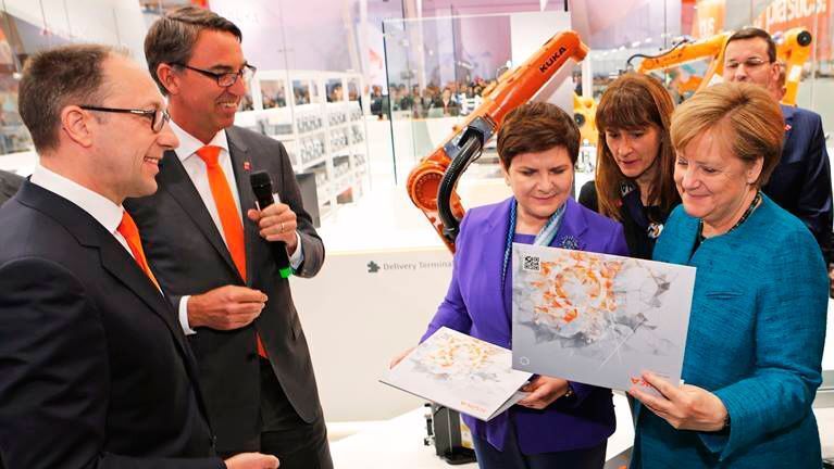 Fresh out of the Smart Factory: Dr. Till Reuter and Peter Mohnen present Angela Merkel and Beata Szydlo an individually produced jigsaw puzzle. (KUKA)