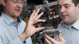 Prof. Andreas Schütze (l.) und Ingenieur Eliseo Pignanelli zeigen auf der Hannover Messe ein Messsystem, das die Ölqualität ständig im Blick hat und voraussagt, wann ein Ölwechsel nötig ist. Das Öl fließt dabei durch eine Messzelle und wird dort mit Infrarotstrahlung durchleuchtet. Wie sichtbar Öl altert, demonstrieren die Ölproben in den Fläschchen: Das linke enthält neues Öl.  (Oliver Dietze,  info@oliverdietze.de)