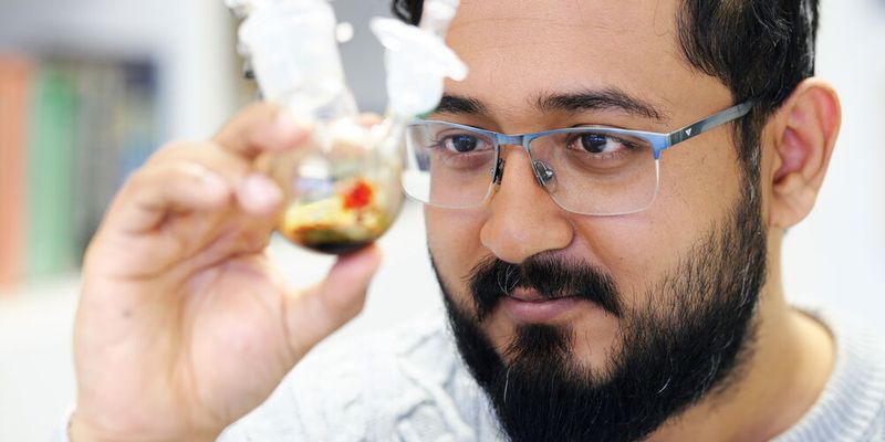 Ankur, Doktorand von Professor David Scheschkewitz, betrachtet die Probe mit Pentasilacyclopentadienid.(Bild:  Thorsten Mohr/UdS)