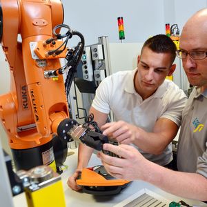 Voith-Mitarbeiter Michél Kratky und Gregor Steinert (r.) von der Chemnitzer Firma Effisi testen die Handsteuerung eines Roboters.