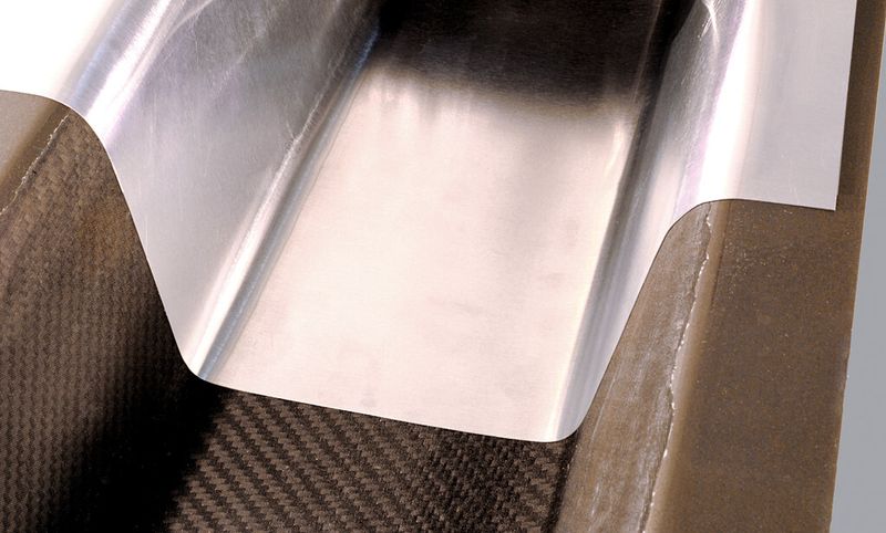 Mit CFK-Prepreg als Kern und Stahl als Deck- und Grundblech entsteht ein Profil, das ohne mechanischen Eigenschaftsverlust das Profilgewicht reduziert. Das ist auch dann der Fall, wenn beim Deckblech Stahl durch Aluminium ersetzt wird. (Bild: ILH, Universität Paderborn)