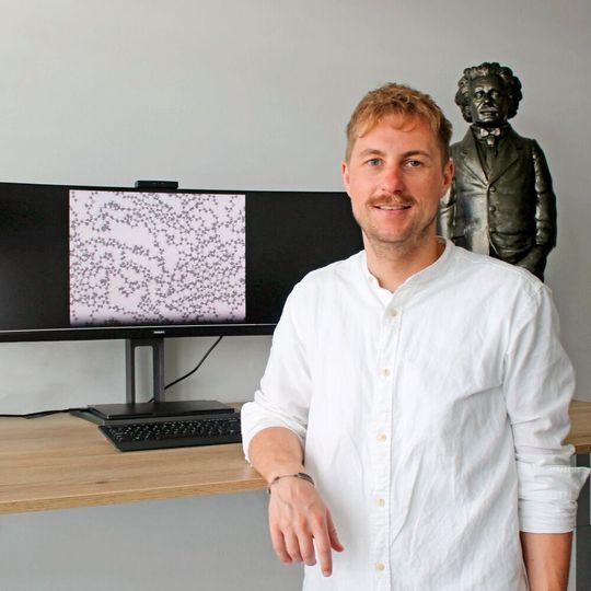 Prof. Dr. Christopher Kuenneth, University of Bayreuth. The screen shows the atomistic structure of a polymer with carbon atoms (gray spheres) and hydrogen atoms (white spheres). Prof. Dr. Christopher Kuenneth, University of Bayreuth. The screen shows the atomistic structure of a polymer with carbon atoms (gray spheres) and hydrogen atoms (white spheres).