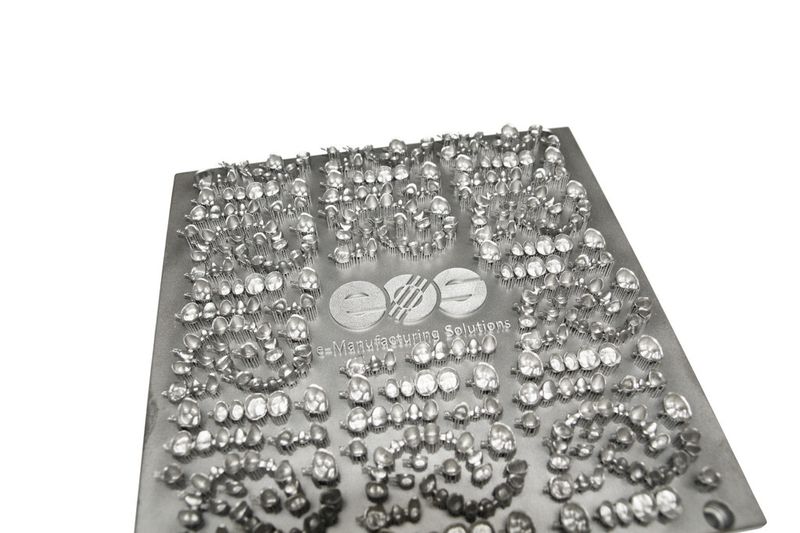 Einen riesigen Produktivitätsfortschritt hat die additive Fertigung per Laser für die Fertigung von Zahnkronen und -brücken gebracht. Dicht gepackt auf einer Platte können die Metallgerüste vollautomatisch hergestellt werden. Lediglich die abschliessende Verblendung erfolgt noch manuell. (Bild: EOS)