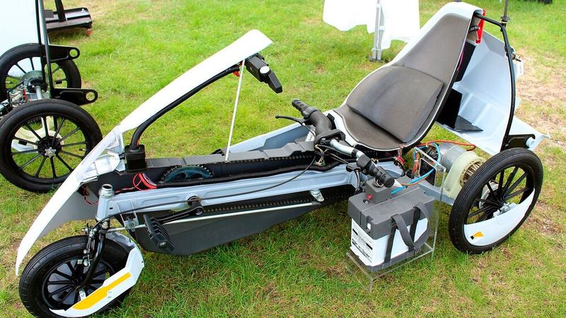 Angetrieben wird der C5 von einem Gleichstrommotor mit 250 W (0,34 PS), welcher über einen kurzen Zahnriemen und mit einem Freilauf versehen nur das linke Hinterrad antreibt und den man mit Pedalen unterstützen kann. In der Betriebsanleitung wird empfohlen, das Anfahren durch Pedalbetätigung zu unterstützen, um die Kohlebürsten des beim Start nur langsam drehenden Motors zu schonen. Den Motor liefert Polymotor, ein Tochterunternehmen von Philips. Ihn speist ein 12 V-Bleiakkumulator von Oldham Batteries mit einer Kapazität von 36 Ah. Insgesamt sollt der Sinclair C5 mit einer Batterieladung rund 32 Kilometer weit kommen. Die Höchstgeschwindigkeit beträgt 24 km/h. (Bild: CC BY-SA 4.0 Prioryman )