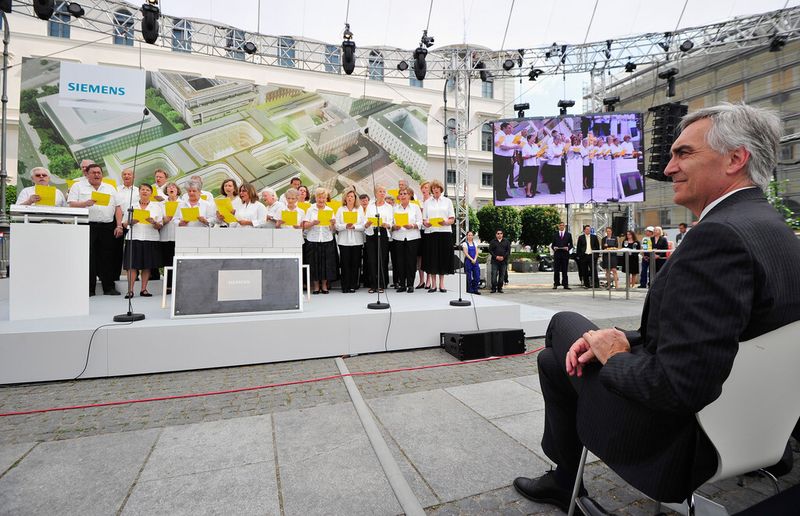Peter Löscher lauscht bei der Grundsteinlegung dem Siemens-Chor (Siemens/Lennart Preiss)