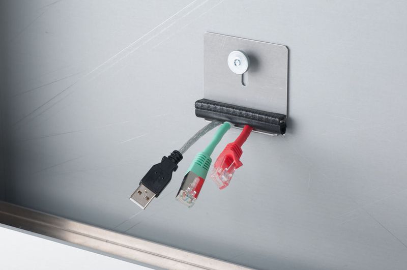 Die sichere Fixierung der Kabel am Einbaurahmen erfolgt über eine Platte mit Rändelschrauben und einen Kantenschutz. (Bopla)