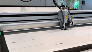 Blick auf den Laserschneidkopf einer 3XL-3200 von Eurolaser, wie er das robuste Polypropylen-Mischgewebe automatisch in Form bringt. Vorbei sind die Zeiten, in denen Mitarbeiter mühsam per Heißschere arbeiten mussten. (Bild: Eurolaser)