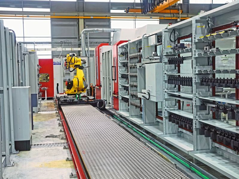 Der auf einer Linearschiene laufende Roboter bedient drei Werkzeugmaschinen, die Koordinatenmessmaschine und die Waschanlage. Material, Paletten und Werkzeug sind in Regalen aufgereiht. (Bild: Klaus Vollrath)