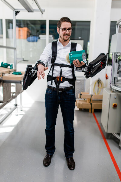 Moritz Hämmerle, Leiter Competence Team Production Excellence am Fraunhofer IAO, testet das Exoskelett in der Modellfabrik. (Bild: Ludmilla Parsyak/Fraunhofer IAO)