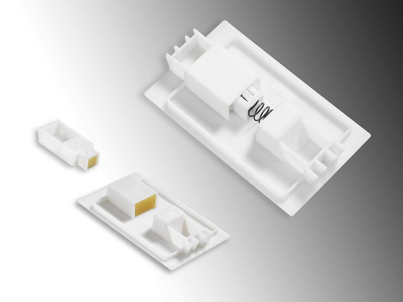 Auf der Euromold 2014 präsentiert Arburg die additive Fertigung eines zweiteiligen Verschlussschiebers. Dabei wird die zweite Austragseinheit des sogenannten Freeformers für den Aufbau von Stützstrukturen genutzt, die sich später leicht entfernen lassen. (Bild: Arburg)