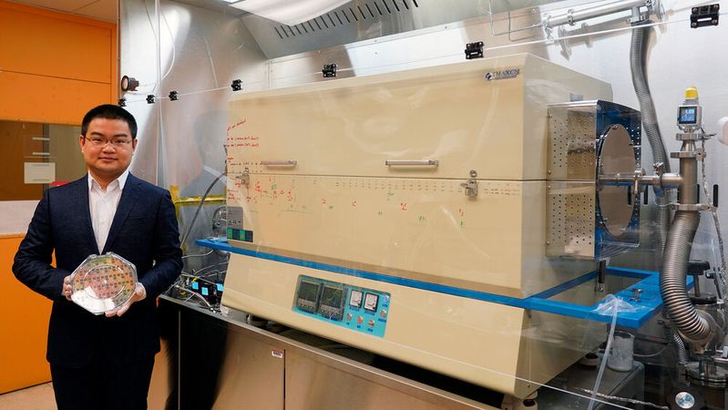 Der Doktorand Jiadi Zhu hält einen 8-Zoll-CMOS-Wafer mit einer Molybdändisulfid-Dünnschicht. Rechts ist der von den Forschern entwickelte Ofen zu sehen, mit dem sie eine Molybdändisulfidschicht auf den Wafer "aufwachsen" konnten, und zwar mit einem Niedrigtemperaturverfahren, das den Wafer nicht beschädigt. Der Doktorand Jiadi Zhu hält einen 8-Zoll-CMOS-Wafer mit einer Molybdändisulfid-Dünnschicht. Rechts ist der von den Forschern entwickelte Ofen zu sehen, mit dem sie eine Molybdändisulfidschicht auf den Wafer "aufwachsen" konnten, und zwar mit einem Niedrigtemperaturverfahren, das den Wafer nicht beschädigt.