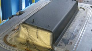 Von der Harzinjektion in die vorgeheizte, evakuierte Form bis zum Entformen des CFK-Bauteils ist nur eine Minute vergangen – ohne Faserverzug. Der Aushärtung folgt die mechanische Bauteilbearbeitung. (Bild: Krauss-Maffei)