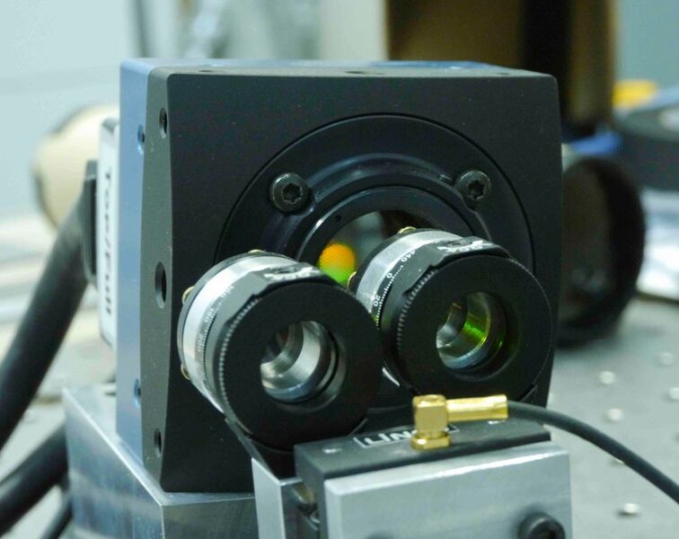 Eine Nahaufnahme der Eosens CL Kamera von Mikrotron mit dem davor positionierten Shack-Hartmann Sensor. Auf dem CMOS Sensor selbst sieht man eine Spiegelung des Kamerabildes – ein Bienenwabenmuster, das von den Mikrolinsen des Shack-Hartmann Sensors gebildet wird. (Bild: Mikrotron)