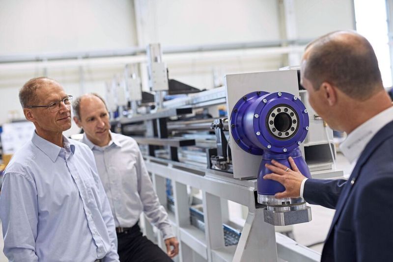 Insgesamt kommen in den Freiform-Biegemaschinen der J. Neu GmbH mehrere Planeten- und Winkelgetriebe zum Einsatz. Im Bild (v.l.):  Lothar Kummermehr, Vertrieb, und Jörg Neu, Geschäftsführer (beide J. Neu GmbH), sowie Michael Stutzer, Vertriebsingenieur bei Wittenstein Alpha.  (Wittenstein)
