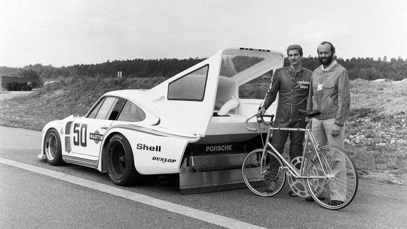 1978 startete Jean-Claude Rude, zu jener Zeit professioneller Bahnradfahrer den Versuch die ungeheure Leistung von 240 km/h auf einem Fahrrad zu erreichen. verschrieben und verfolgte das Ziel mit all seiner Energie. Am Mittwoch, den 23. August um starten Rude und der Rennfahrer Henri Pescarolo mit einem Porsche 935 mit Spezialaufbau am Heck um 10.30 Uhr auf dem Volkswagen-Testgelände in Ehra-Lessien bei Wolfsburg. Doch plötzlich passiert es: Rude verliert die Kontrolle über sein Rad. Der hintere Schlauchreifen löst sich mit einem Ruck von der Felge, verwickelt sich zwischen Rad und Rahmen. Das Rad blockiert, die Felge wetzt über die Fahrbahn. Rude gelingt es, das schleudernde Vehikel „wie ein Skifahrer“ im Griff zu halten und auf der Felge über die Bahn zu schlittern, bis er an Geschwindigkeit verliert und nach einigen hundert Metern zum Stehen kommt. Unverletzt bleibt es bei diesem einen Versuch. (Bild: Porsche AG)