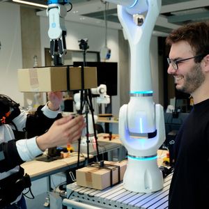 Federico Masiero (li. mit Exoskelett) und Emanuele Aimi testen die Zusammenarbeit mit einem Roboter von Neura Robotics. (Bild:  Andreas Schmitz / TUM)