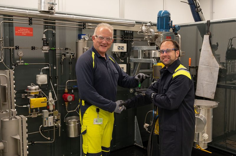 Projektleiter Martin Schneider (l.) übergibt den Schlüssel an Mark Seper, der als Leiter der Verfahrenstechnik viele Versuche auf der nagelneuen Anlage fahren und das Wissen um den komplexen Stoff Bitumen erweitern wird. (Bild: Pörner)