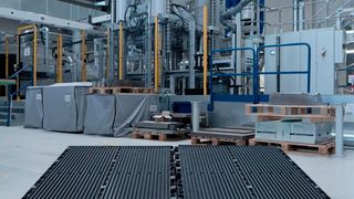 Die beiden schwarzen Bauteile vor dieser Wickert-Presse haben bewiesen, dass man leichte Batteriegehäuse für die E-Mobilität wirtschaftlich auch aus faserverstärkten Thermoplasten herstellen kann. Das brachte dem Team der TU Chemnitz den JEC Innovation Award 2026 ein. (Bild: TU Chemnitz)