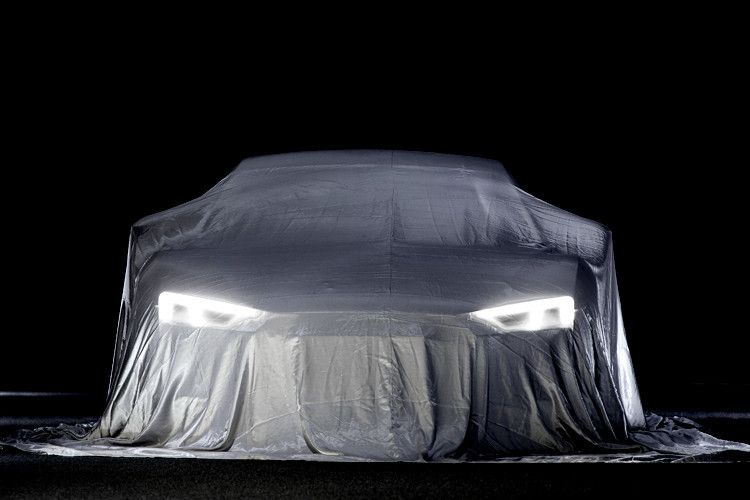 Bislang lässt der Premuimhersteller nur die Laserlichter leuchten. Ansatzweise ist dennoch die Grillform durch das Tuch zu erkennen. (Foto: Audi)