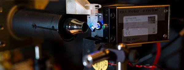 Prototyp des adaptiven PCR (PCR = polymerase chain reaction): Die kleine Probe in der Mitte wird durch einen Laser auf der rechten Seite angeleuchtet. Unterschiedliche Ebenen der Fluoreszenz werden mittels eines Spektralphotometers auf der linken Seite gesammelt und ermöglichen die Kontrolle der DNA-Duplikation.(Bild:  Anne Rayner, Vanderbilt University)