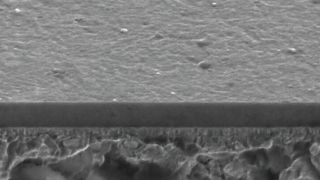 Mittels 90-Grad-Plasmafilterung hergestellte, etwa 2,5 Mikrometer messende „ta-C“-Schicht. Wiederum die Schrägansicht auf die Bruchfläche im Rasterelektronenmikroskop. (Bild: Fraunhofer IWS)