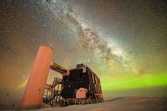 Ein Blick auf das Icecube-Labor bei einem sternenklaren Nachthimmel, der die Milchstraße und grüne Polarlichter zeigt. (Bild:  Yuya Makino​/​IceCube, NSF)