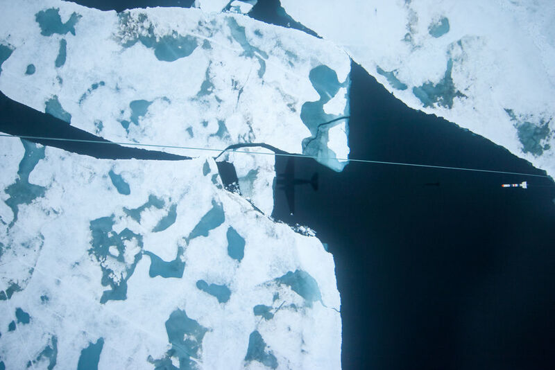 Der AWI-Meereisdickensensor beim Messflug über arktischem Meereis. Aufnahme von der Flugzeug-Kampagne TIFAX 2016, bei der AWI-Meereisphysiker von der grönländischen Station Nord aus zu Messflügen in die Zentrale Arktis gestartet sind. Das Foto wurde mit jener Kamera gemacht, die in den Rumpf des Forschungsflugzeuges eingebaut ist und senkrecht nach unten fotografiert. (Alfred-Wegener-Institut / IceCam)