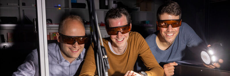 Lysander Huberich (left), team leader Bruno Schuler (middle) and optics specialist Jonas Allerbeck at the THz optics, which generates picosecond-precise excitation pulses.
