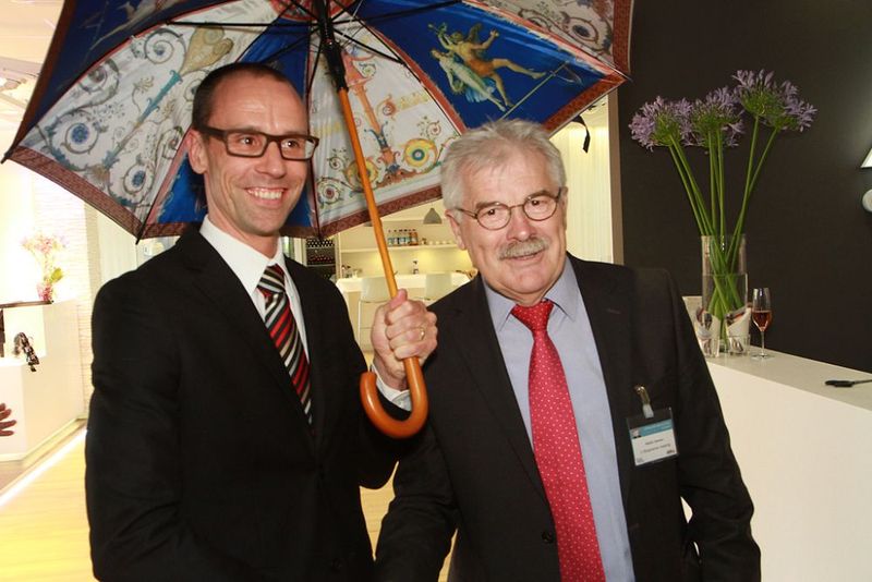 Ismanings 2. Bürgermeister, Walter Stenner, schenkte Edwin Roobol, Regional Director Middle Europe bei Axis, einen Regenschirm mit Innenansichten aus dem Ismaninger Schloss. (Bild: Axis)