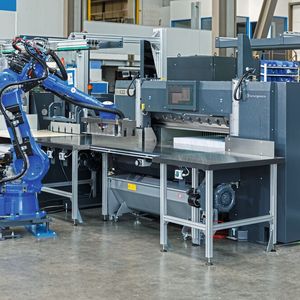 Ein Roboter Motoman GP50 von Yaskawa übernimmt an der Schneidemaschine das Handling des Papierstapels und kann dabei das Fingerspitzengefühl eines menschlichen Bedieners simulieren.(Bild:  Independent light gmbh)