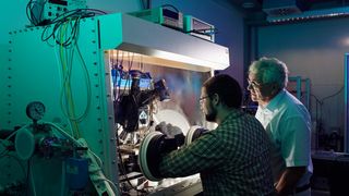 Prof. Heinz von Seggern (li.) und Tobias Könyves-Toth (re.) an der Maschine. Die Faserbeschichtung muss unter Vakuumbedingungen stattfinden. (Katrin Binner)