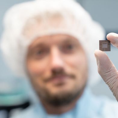 Weg mit zuviel Wärme! Trumpf hat es mit Lasertechnik geschafft, eine Kühlung für die KI-Chips der nächsten Generation herzustellen, die gestapelt werden, um mehr zu leisten. Hier hält ein Trumpf-Mitarbeiter einen solchen Chip mit integriertem Kühlsystem zwischen den Fingern. (Bild: Trumpf)