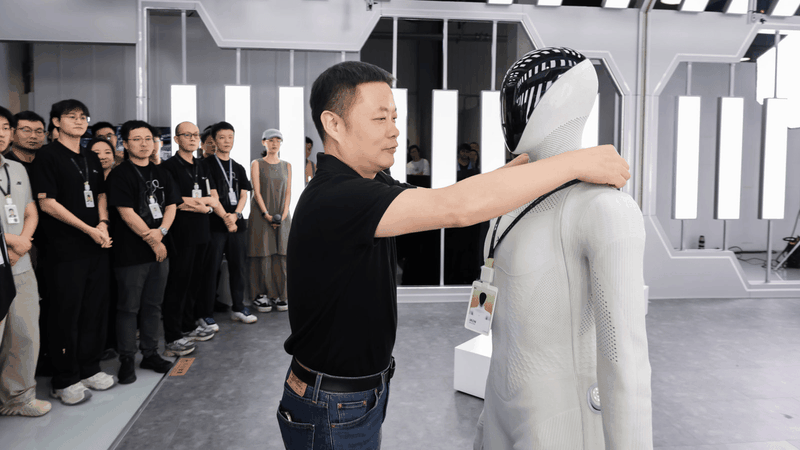 He Xiaopeng hängt dem Humanoiden „IRON“ einen Mitarbeiterausweis um den Hals, als Teil des Teams.(Bild:  Xpeng)