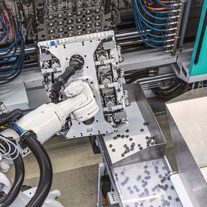 Der KR Quantec, der maximale Wiederholgenauigkeit und kontinuierliche Präzision erreicht, hat Zugriff auf die Spritzgussmaschine. Er entnimmt simultan zum Spritzzyklus die Rollen aus ihrem unteren Teil und setzt sie in die Steckbuchsen ein, um die fertigen Teile aus Kunststoff danach zu entnehmen und auf dem Förderband abzulegen.(Bild:  Kuka Group)