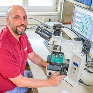 Maximilian Stummer, Head of Research at INOCON Technologie GmbH, Plasma Innovations' sister company specializing in technology development, uses a microscope to check the manufacturing quality of a Flexxalumina printed circuit board produced by Croll Technology Limited (CRT) in Shenzhen.(Image: Wolfgang Simlinger)