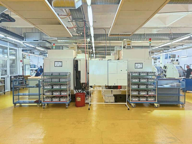 Les deux lignes de trois Robodrill, chacune alimentée par son propre chariot Kanban : rondelles d'un côté, barquettes de l'autre. Une standardisation qui permet aux robots de tourner sans nouveau réglage, quelle que soit la série en cours. (Source : Marina Hofstetter)