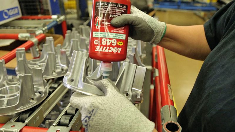 Ein Polaris-Monteur trägt den Fügeklebstoff «Loctite 648» auf den Innendurchmesser der Treibscheibe für die Antriebskupplung auf. Anschliessend werden die Lager eingepresst. (Bild: Henkel)