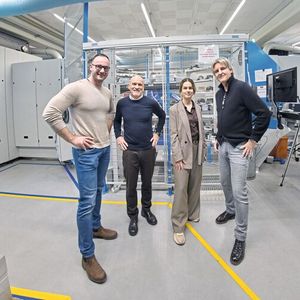 Die SMM-Redaktion hat mit den Spezialisten von Eugen Seitz und Heller über die flexible Fertigungslösung diskutiert. Im Bild (v. l. n. r.): Tobias Fischer (Operations Manager, Eugen Seitz AG), Christoph Andris (Verkaufsleiter, Heller Schweiz), Abetare Yaves (Leitung Sales & Marketing, Vogel Communications Group AG) und Thomas Girelli (COO,Eugen Seitz AG). Im Hintergrund einer der beiden Fertigungsinseln, mittig die Goodj-Automation, rechts und links sind die beiden Heller «HF 3500» angedockt. (Bild:  Matthias Böhm)