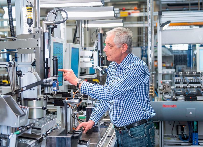 Ein Mitarbeiter bedient an der vernetzten Multiproduktlinie von Bosch ein Touch-Panel zur Auswahl eines Montageprogramms. (Bild: Bosch)