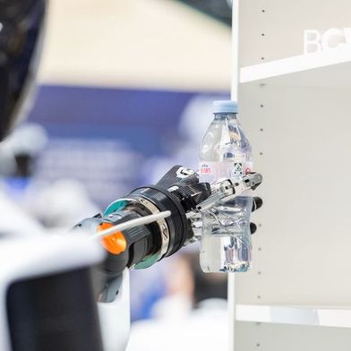 A humanoid robot takes a beverage from the shelf and places it on the counter. The demonstration at Bosch Connected World 2026 showcased key capabilities of humanoid systems in a specific handling process. (Image:Image: Schunk SE & Co. KG)