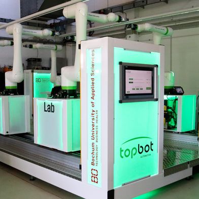 Die grüne Beleuchtung zeigt, dass die Roboter einsatzbereit sind und alles sicher ist. Sobald jemand zu nah an einem der Roboterarme steht, schaltet die Beleuchtung auf rot und die Roboter stoppen. (Bild: Judith Merkelt-Jedamzik, HSBO)