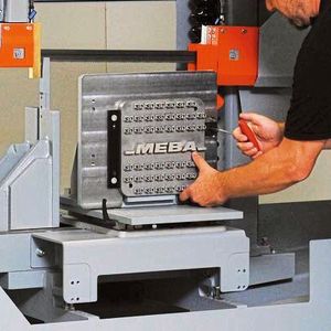 Der Bediener fixiert hier die Grundplatte per Schnellspannung. Als „Bauteile“ sind hier der Schriftzug Meba und mehrfach das Kürzel 3D gedruckt worden.