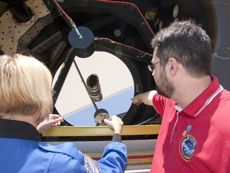 Thomas Keilig, telescope assembly manager des German SOFIA Institute erläutert einer Lehrerin den Hauptspiegel (NASA)