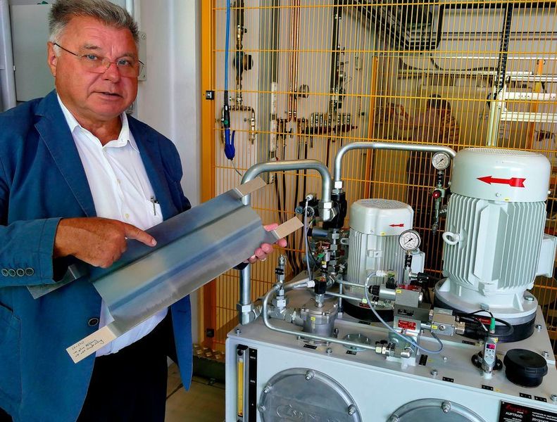 Konrad Schnupp, Geschäftsführer der Schnupp GmbH & Co. Hydraulik KG in Bogen mit einem fertig pressgehärteten Versuchsteil neben dem außerhalb der Schutzzone installierten Hydraulikaggregat. „Wir sind mit Vert Press zwar noch in der Erprobungsphase, aber die Ergebnisse sind vielversprechend, dass sich dieses völlig neuartige Verfahren industriell etablieren lässt“, meint der erfahrene Umformspezialist. (Kuhn)